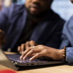 African American man and woman sits at a stylish home office, brainstorming ideas for their digital business, using modern technology to improve communication and project efficiency.